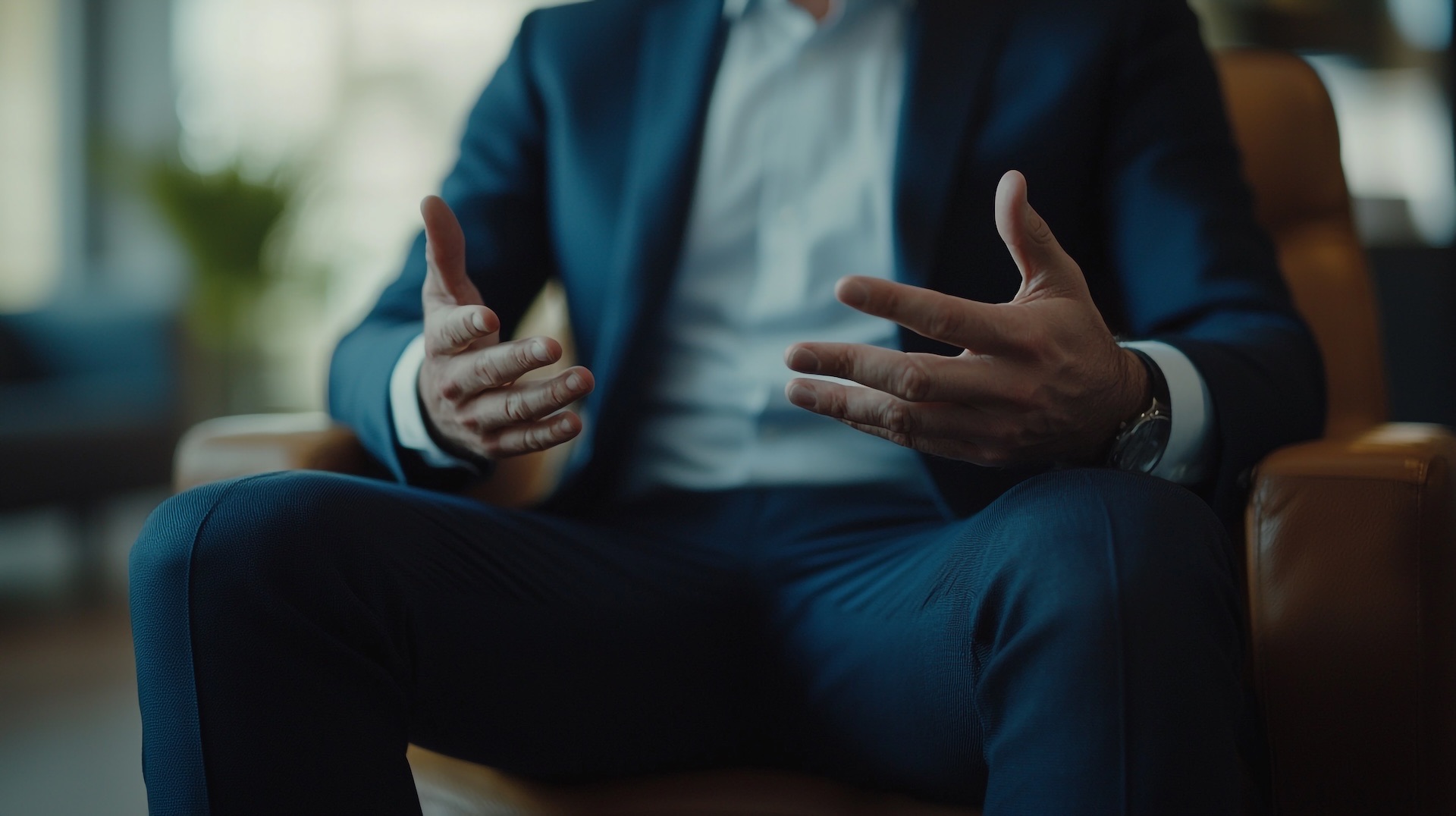 A lawyer in a navy suit sits in a leather chair speaking with a psychologist.